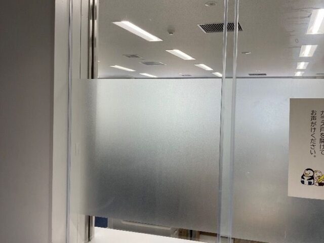 受付窓の透明ガラス 四方糸面フチ磨き加工 室内側引き手掘り加工1箇所 外側全面透明飛散防止フィルム貼り 室内側フロストフィルム部分貼り交換｜福岡市中央区の施工写真