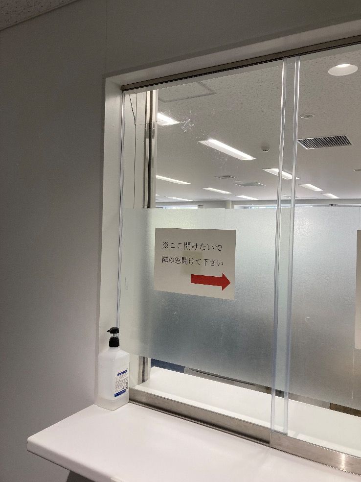 福岡市中央区受付窓ガラスの透明ガラス5㎜厚 四方糸面フチ磨き加工 室内側引き手掘り加工1箇所 外側全面透明飛散防止フィルム貼り 室内側フロストフィルム部分貼りが割れている施工前の様子